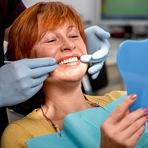 Older woman in dental chair looking at smile