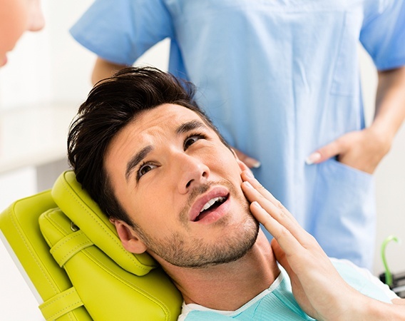 Man in dental chair holding jaw